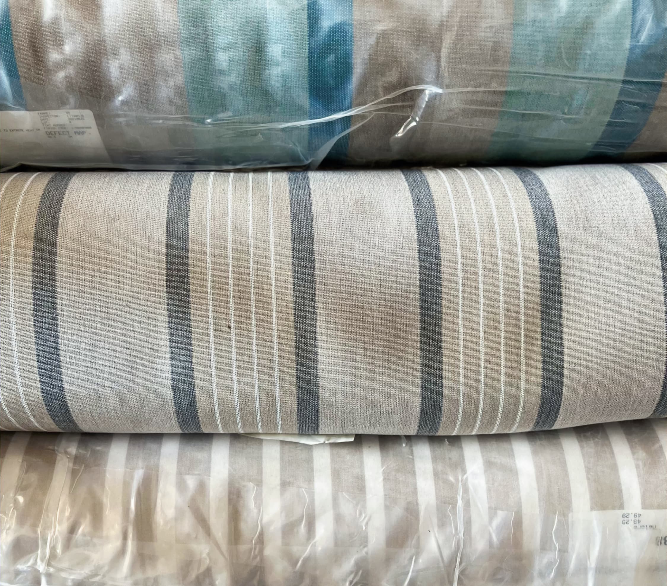 Surplus contract-grade roll goods at Core Products Group — striped upholstery fabric on the rack, tagged for inventory